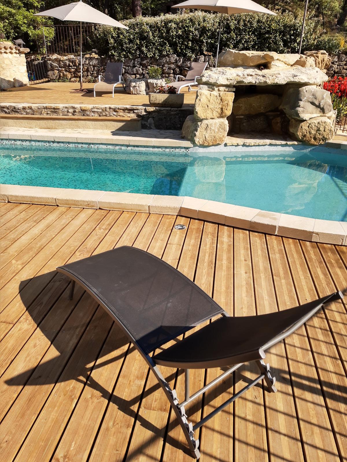 Bord de piscine en bois et grotte en pierre