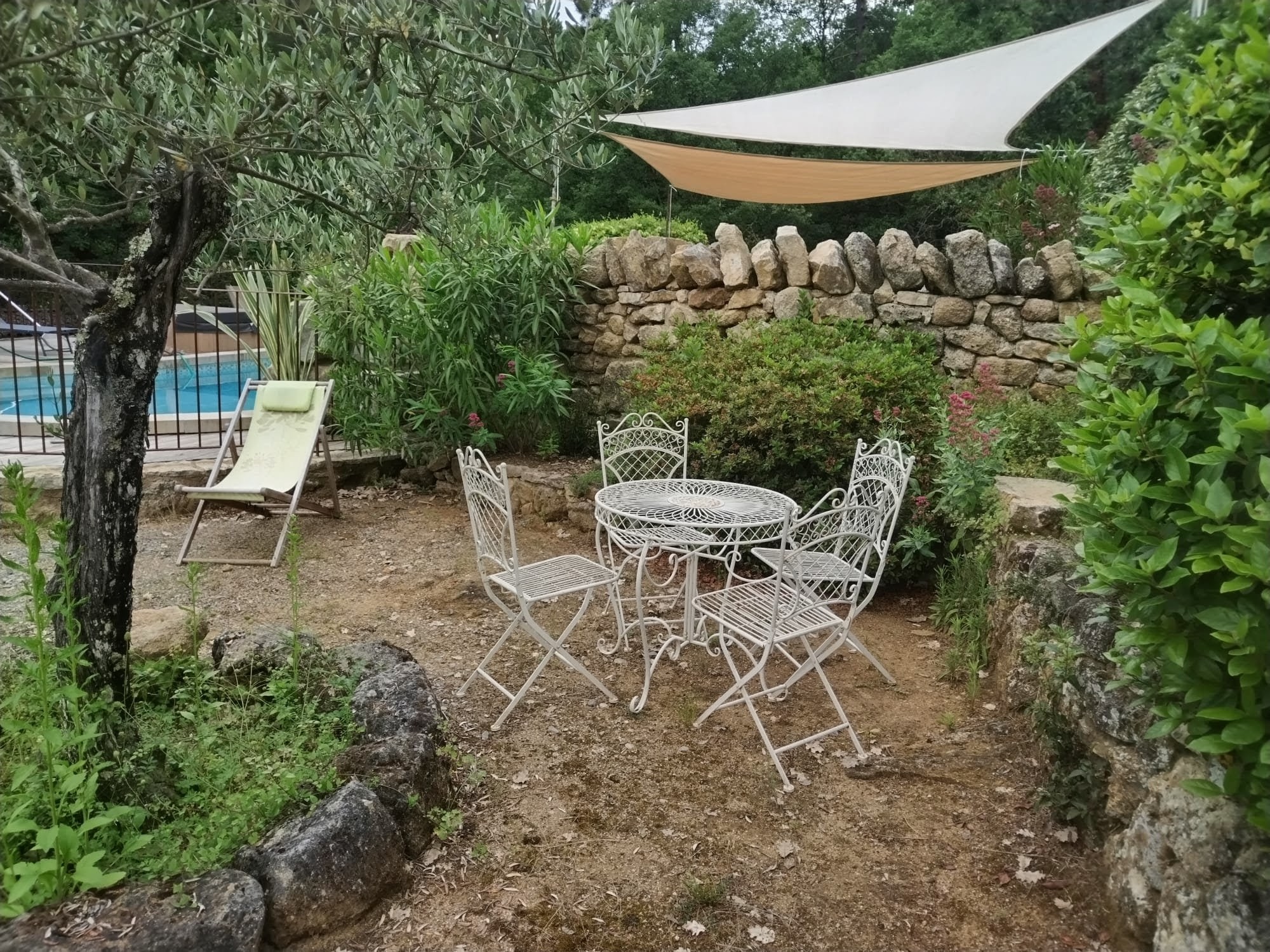 Salon de jardin sous voile d'ombrage près de la piscine